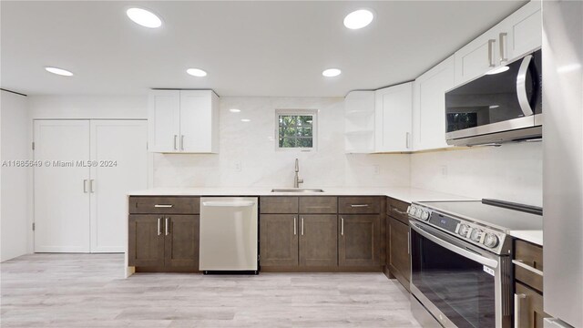 837 El Rado St, Coral Gables, FL 33134 - kitchen with stainless steel appliances, a sink, dark brown cabinetry, white cabinets, and light countertops