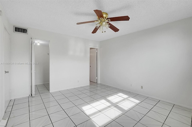 unfurnished room with ceiling fan, a textured ceiling, and light tile patterned floors