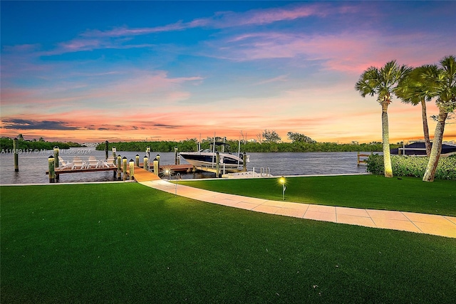 exterior space featuring a dock, a lawn, and a water view