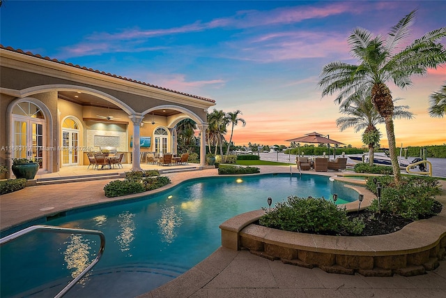 pool at dusk featuring french doors and a patio