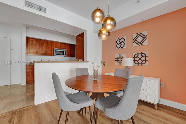 dining area featuring a high ceiling and light hardwood / wood-style flooring