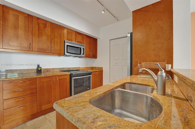 kitchen featuring track lighting, sink, light tile patterned flooring, light stone countertops, and appliances with stainless steel finishes