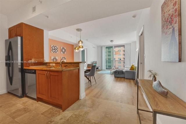 kitchen with stainless steel appliances, kitchen peninsula, sink, pendant lighting, and light hardwood / wood-style flooring