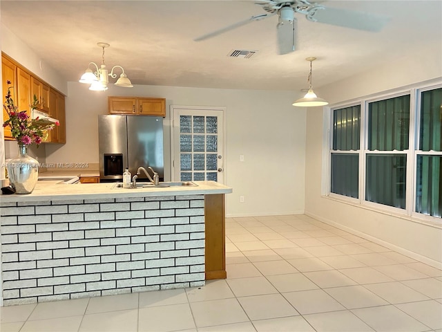 kitchen featuring ceiling fan with notable chandelier, light tile patterned floors, sink, pendant lighting, and stainless steel fridge