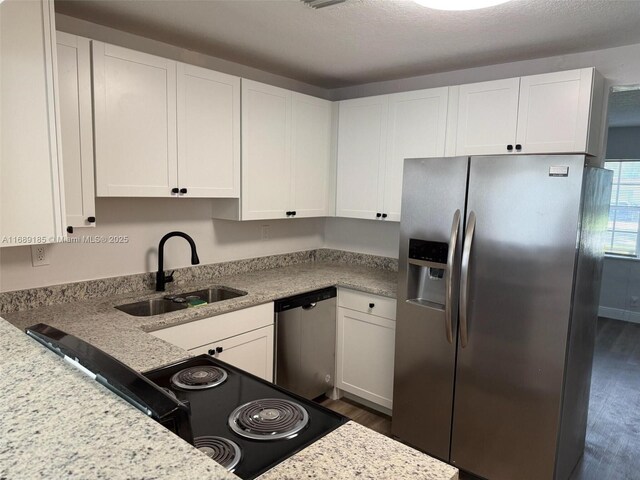 kitchen with light stone countertops, sink, white cabinets, and appliances with stainless steel finishes