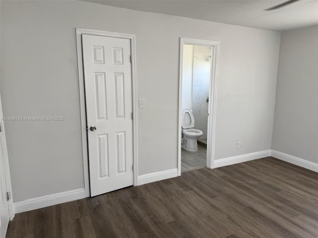 unfurnished bedroom with dark hardwood / wood-style flooring, ceiling fan, and connected bathroom