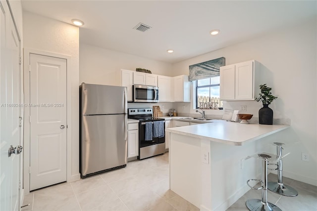 kitchen with kitchen peninsula, white cabinetry, sink, and appliances with stainless steel finishes