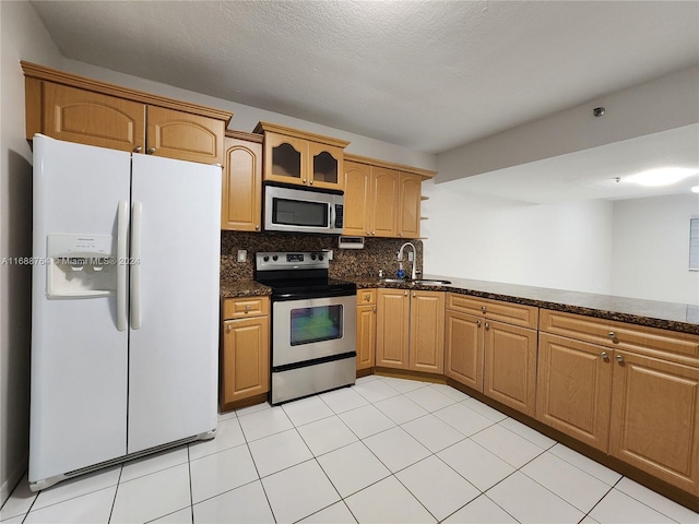 kitchen with stainless steel appliances, sink, tasteful backsplash, dark stone counters, and a textured ceiling