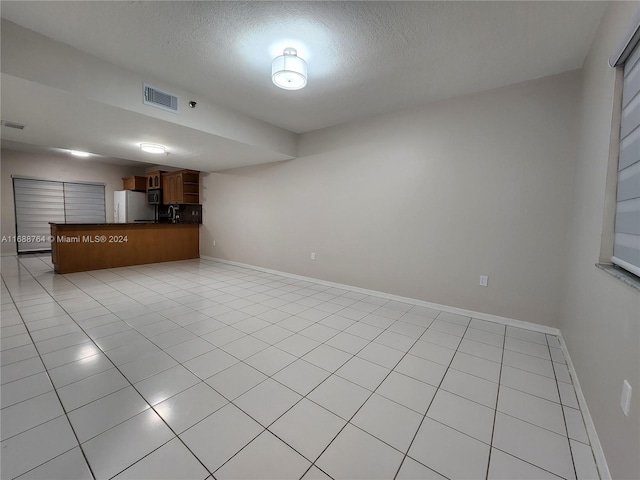 interior space featuring a textured ceiling and light tile patterned floors