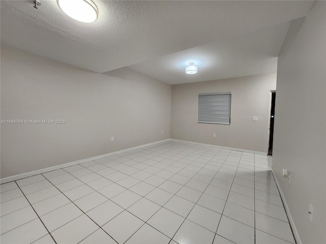 tiled empty room with a textured ceiling