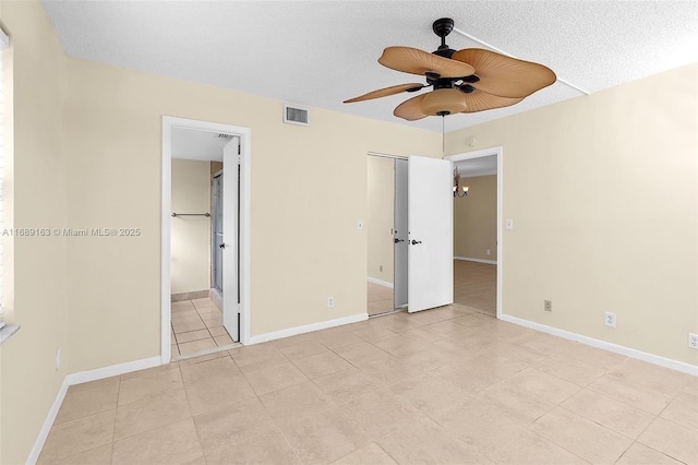 unfurnished bedroom with ceiling fan, connected bathroom, a textured ceiling, and light tile patterned floors