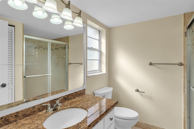 bathroom with vanity, a shower with shower door, and toilet