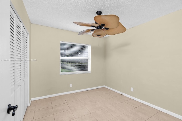 unfurnished bedroom with ceiling fan, a closet, light tile patterned flooring, and a textured ceiling