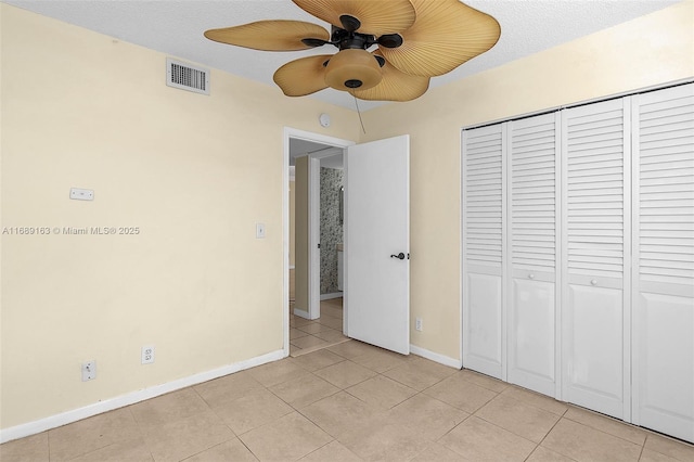 unfurnished bedroom featuring light tile patterned floors, a closet, and ceiling fan