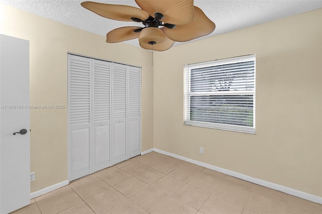 unfurnished bedroom featuring light tile patterned floors, a closet, a textured ceiling, and ceiling fan