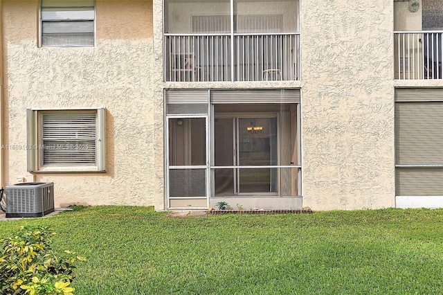 entrance to property featuring a yard and central AC unit