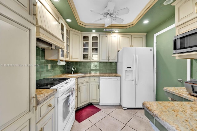 kitchen featuring white appliances, cream cabinets, ceiling fan, a tray ceiling, and light tile patterned flooring