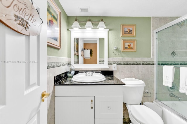 full bathroom featuring vanity, toilet, enclosed tub / shower combo, and tile walls