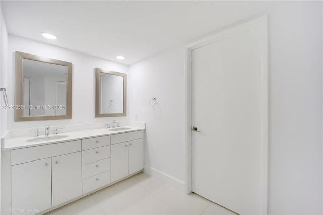 bathroom with double vanity, recessed lighting, baseboards, and a sink