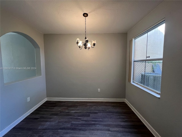 empty room with an inviting chandelier and dark hardwood / wood-style flooring