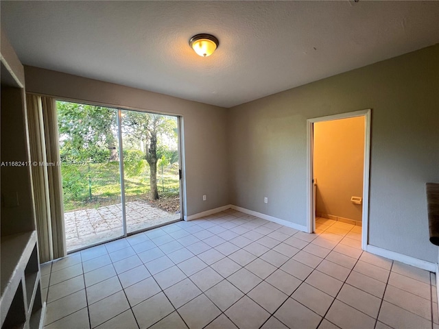 unfurnished room with a textured ceiling and light tile patterned floors