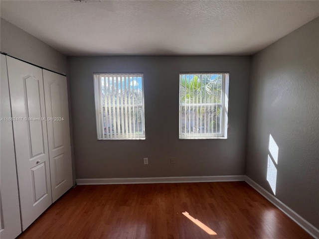 unfurnished bedroom featuring a closet, hardwood / wood-style floors, and a textured ceiling