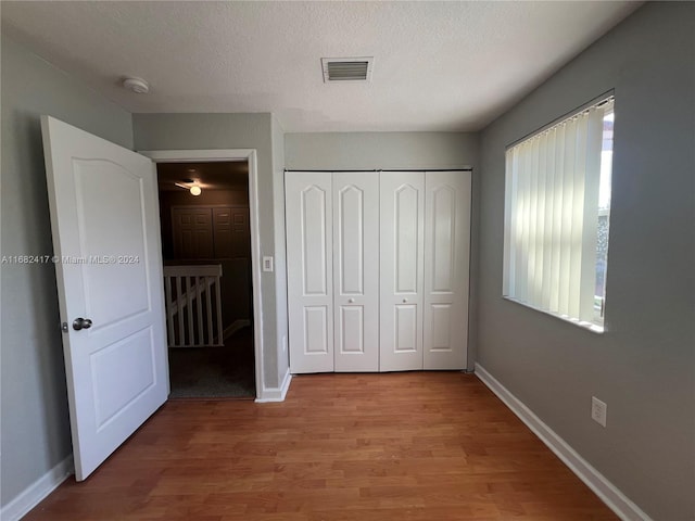 unfurnished bedroom featuring a textured ceiling, a closet, and light wood-type flooring