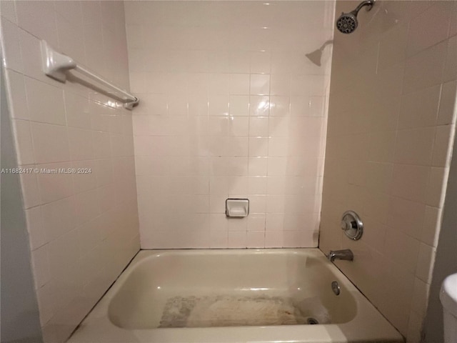 bathroom featuring tiled shower / bath combo and toilet