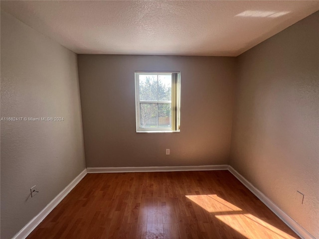 empty room featuring a textured ceiling and hardwood / wood-style flooring