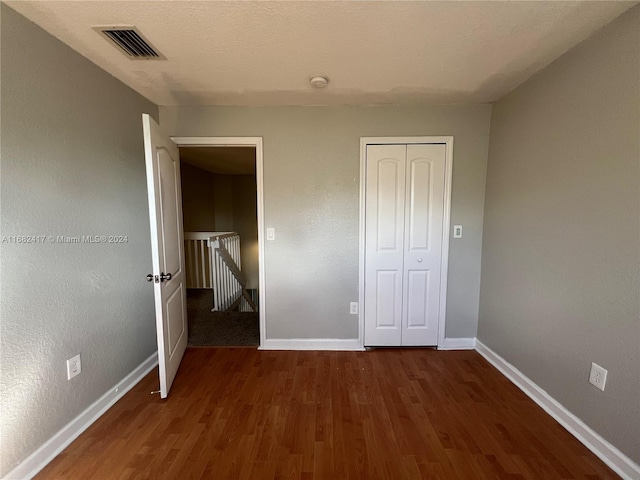 unfurnished bedroom with a closet and dark hardwood / wood-style flooring