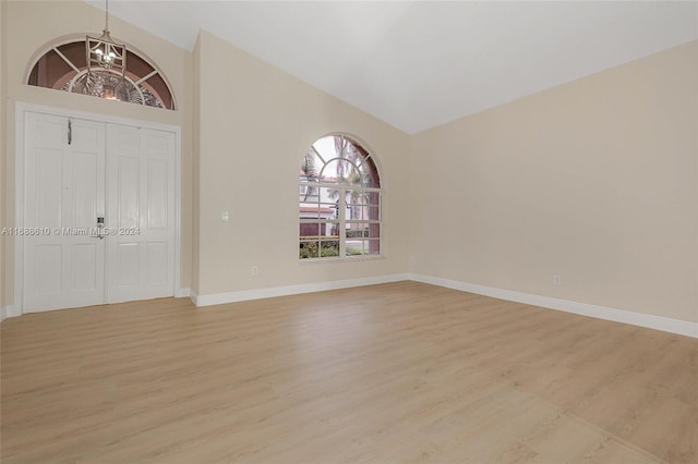 entrance foyer featuring high vaulted ceiling, a notable chandelier, and light hardwood / wood-style flooring