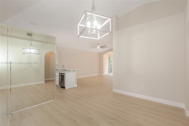 interior space featuring ceiling fan with notable chandelier, sink, light wood-type flooring, and vaulted ceiling