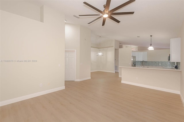 unfurnished living room featuring light hardwood / wood-style floors and ceiling fan with notable chandelier