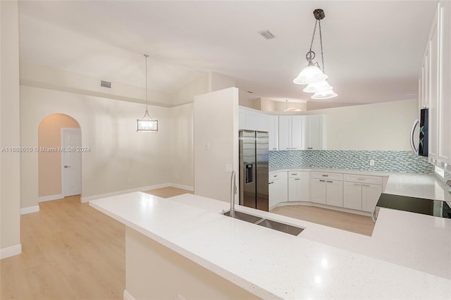 kitchen featuring white cabinets, kitchen peninsula, decorative light fixtures, and stainless steel appliances