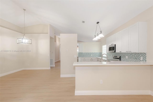 kitchen featuring stainless steel appliances, light hardwood / wood-style floors, kitchen peninsula, tasteful backsplash, and white cabinets