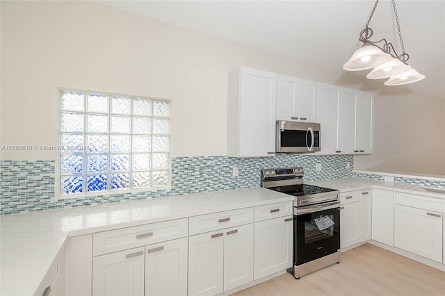 kitchen featuring stainless steel appliances, white cabinetry, tasteful backsplash, decorative light fixtures, and light wood-type flooring