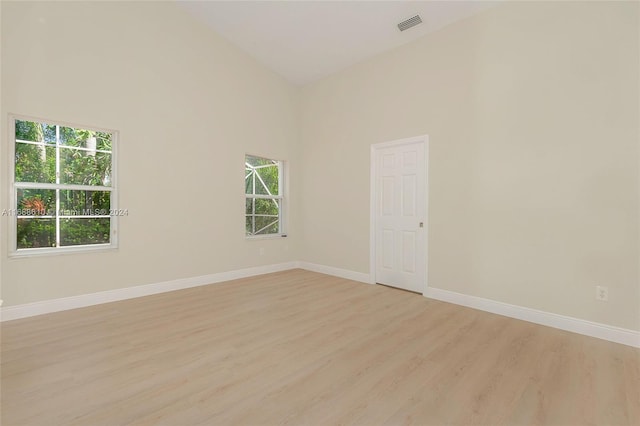 spare room featuring high vaulted ceiling, plenty of natural light, and light wood-type flooring