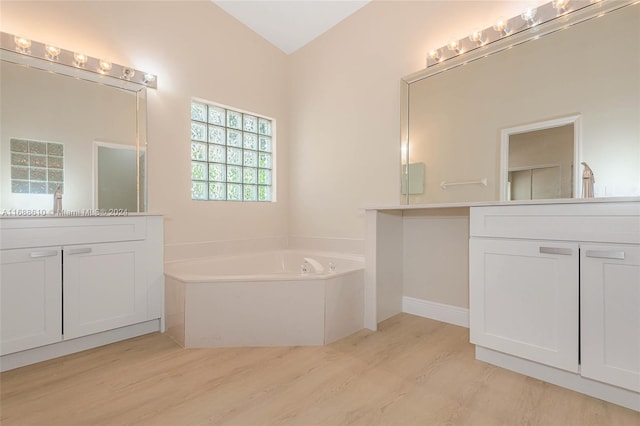 bathroom with wood-type flooring, vanity, a bathing tub, and lofted ceiling