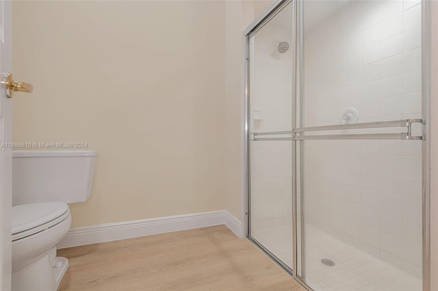 bathroom with an enclosed shower, hardwood / wood-style flooring, and toilet