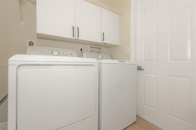 laundry area with cabinets, washing machine and clothes dryer, and light hardwood / wood-style floors