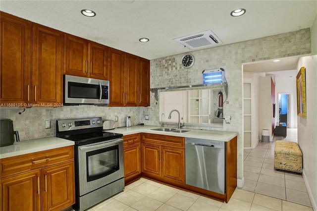 kitchen featuring stainless steel appliances, light tile patterned floors, sink, and backsplash