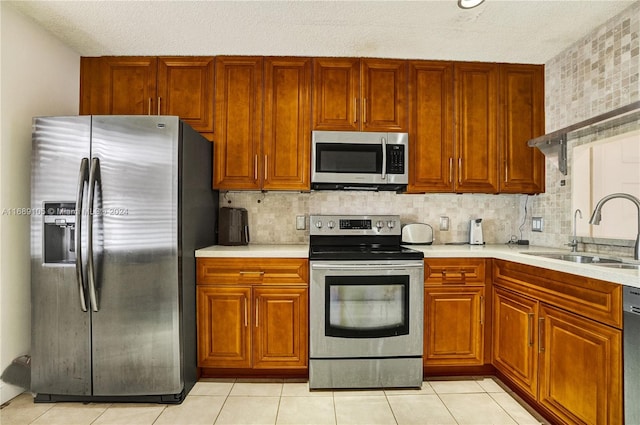 kitchen with decorative backsplash, appliances with stainless steel finishes, sink, and light tile patterned flooring