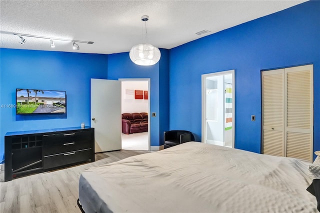 bedroom featuring ensuite bath, a textured ceiling, and light hardwood / wood-style flooring