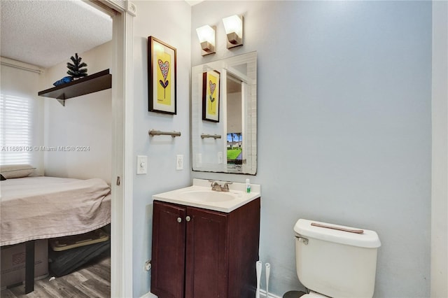 bathroom featuring vanity, wood-type flooring, a textured ceiling, and toilet