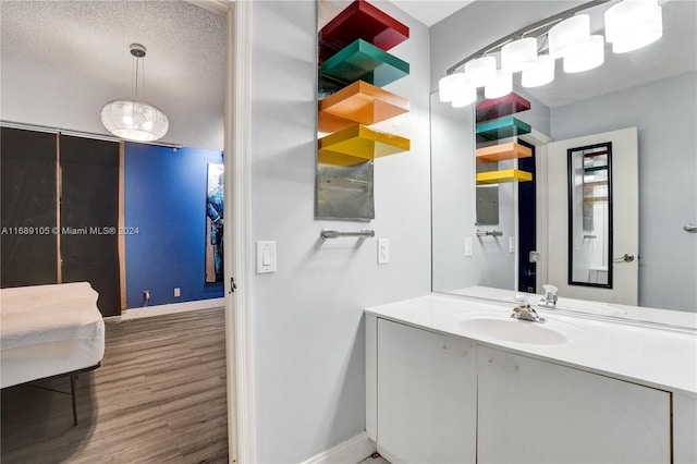 bathroom with hardwood / wood-style floors, a textured ceiling, and vanity