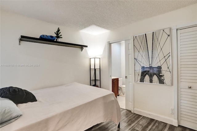 bedroom featuring connected bathroom, dark wood-type flooring, and a textured ceiling