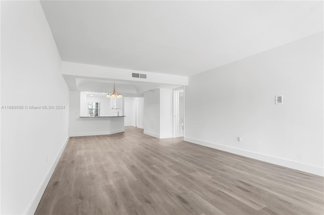 unfurnished living room featuring hardwood / wood-style flooring and an inviting chandelier