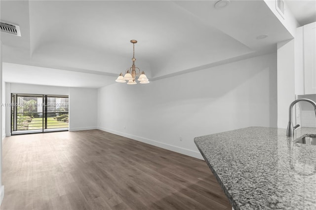 interior space with dark wood-type flooring, white cabinetry, pendant lighting, and light stone counters