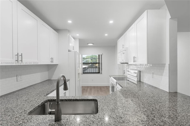 kitchen with white cabinetry, sink, white appliances, and dark stone countertops