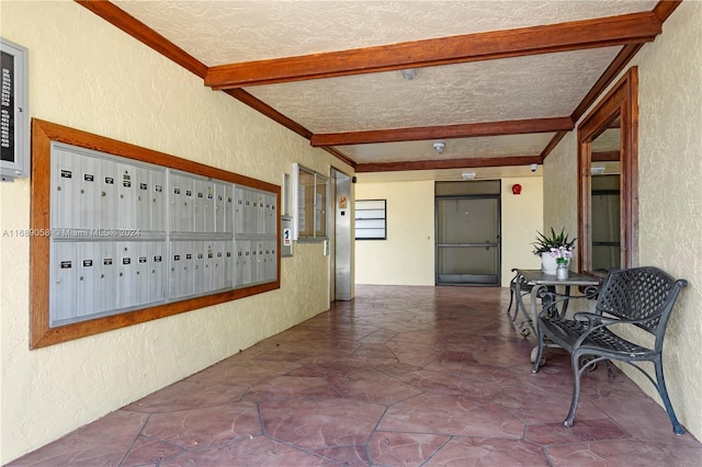 corridor featuring a mail area, beamed ceiling, a textured ceiling, and ornamental molding